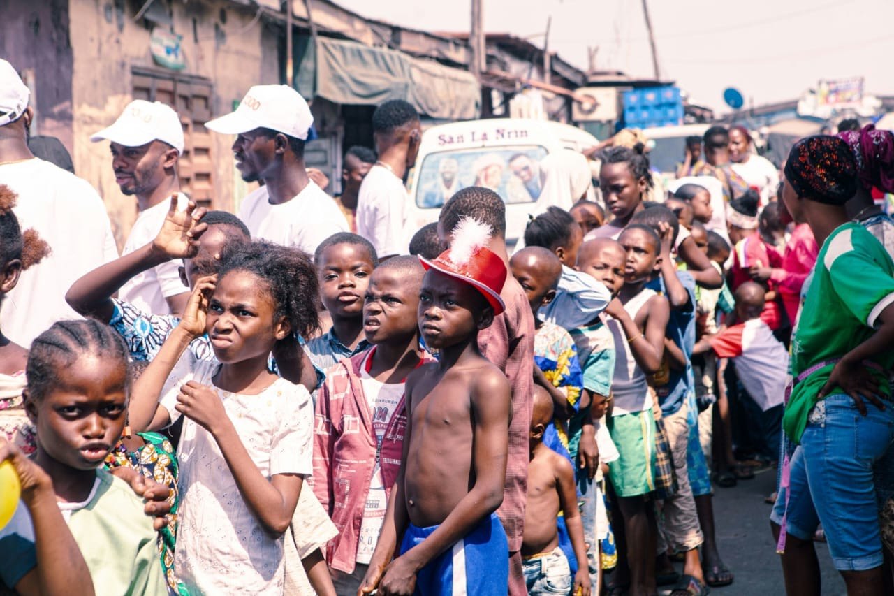 Children and adults gathered together in a busy street