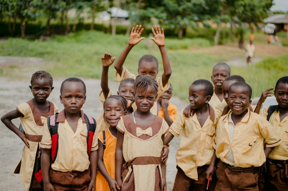 Schoolchildren in uniform waving and smiling outdoors