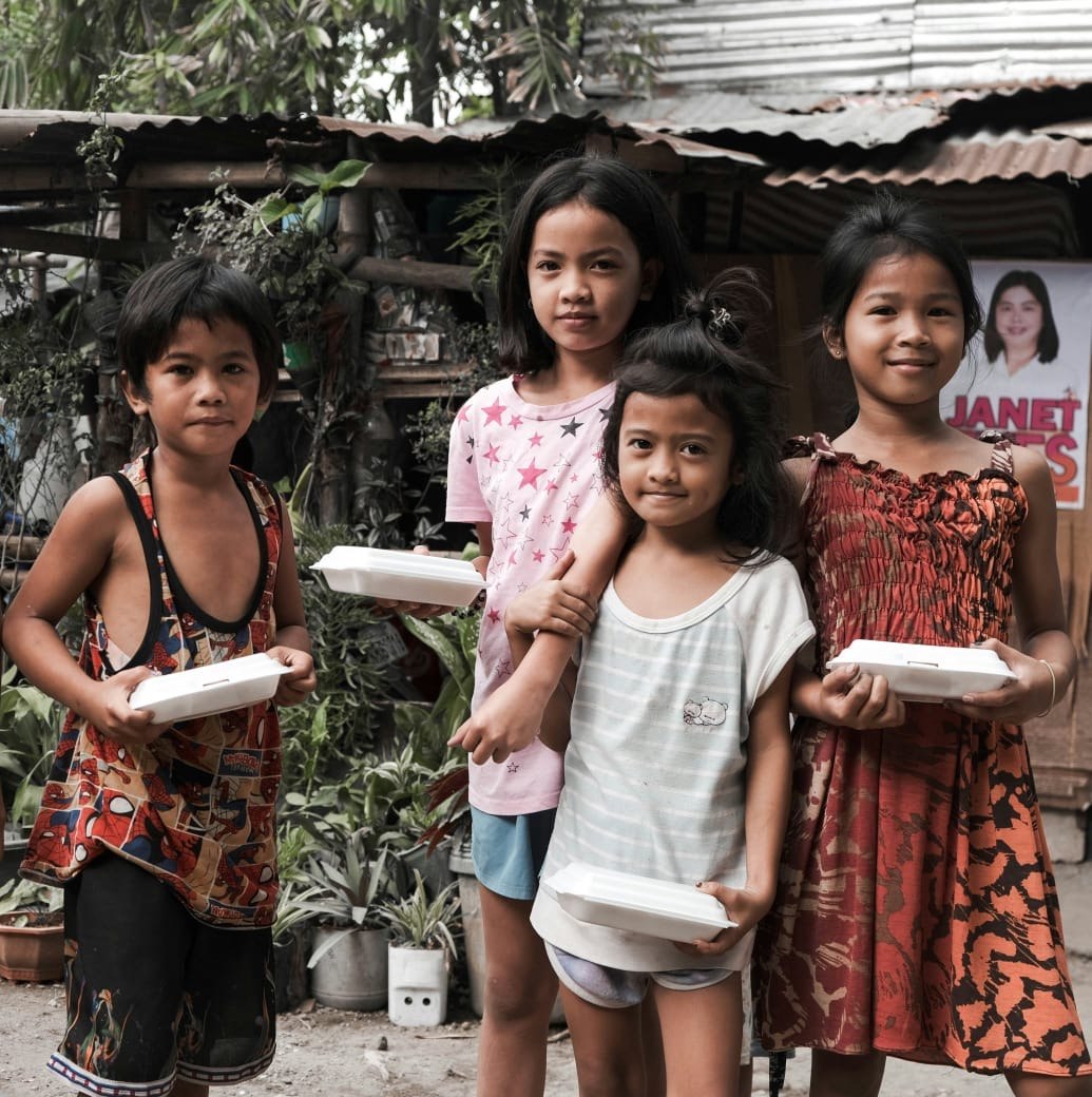 Children holding food boxes during a meal distribution